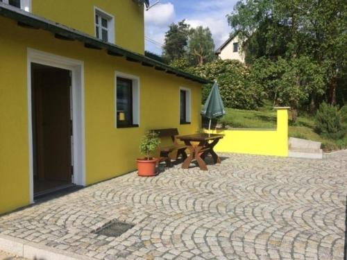 żółty dom ze stołem i patio w obiekcie Ferienhaus in Bad Elster mit Kleinem Kamin w mieście Bad Elster