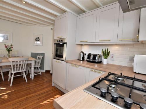 a kitchen with white cabinets and a dining table at 3 Bed in Conwy TYPLL in Llangelynin