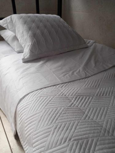 1 cama no hecha con sábanas y almohadas blancas en HABITACIÓN COMPARTIDA MIXTA EN MIRAFLORES DE FAMILIA CON PRINCIPIOS Y VALOREs, en Lima