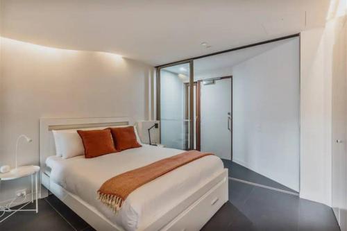 a bedroom with a large white bed with orange pillows at Apartment nestled between Lake Burley Griffin, city and ANU in Canberra