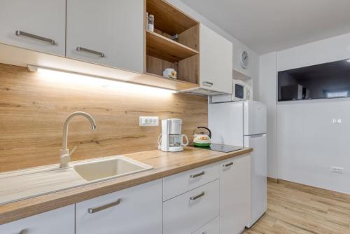 a white kitchen with a sink and a refrigerator at Nettes Appartement in Rovinj mit Garten, Terrasse und Grill in Rovinj