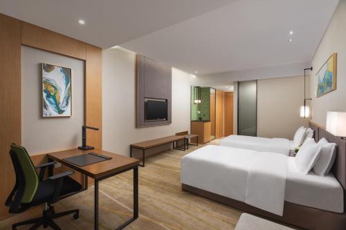 a bedroom with a bed and a desk and a tv at Holiday Inn Chengdu Airport by IHG - Free Shuttle to Shuangliu International Airport in Chengdu