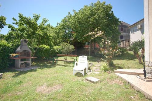 a yard with two white chairs in the grass at Ferienwohnung für 4 Personen ca 65 qm in Bogovići, Kvarner Bucht Krk in Malinska