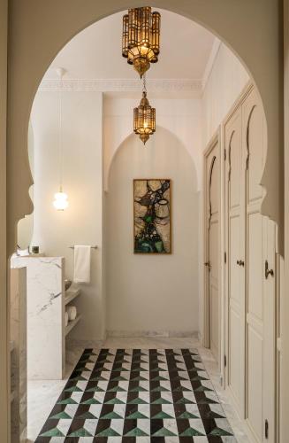 a hallway with a chandelier and a checkered floor at Riad Dar Al Dall - This Time Tomorrow in Marrakech in Marrakech