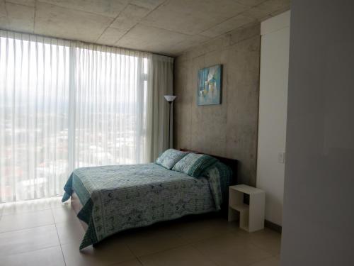 a bedroom with a bed and a large window at iFreses, Study Full equipped whith Pool, air- conditioning, spectacular view of the city, parking with additional payment in Curridabat