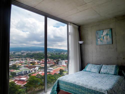 a bedroom with a bed and a large window at iFreses, Lofts Full equipped whith Pool, air-conditioning, spectacular view of the city in Curridabat