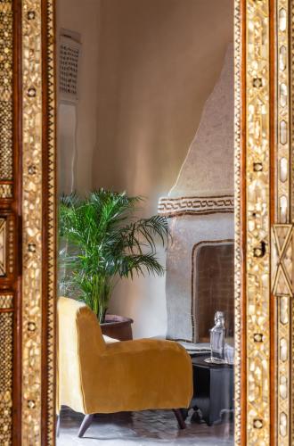 a living room with a yellow chair and a fireplace at Riad Dar Al Dall - This Time Tomorrow in Marrakech in Marrakech