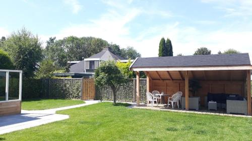 une arrière-cour avec un hangar doté d'une table et de chaises dans l'établissement Ferienhaus am Meer mit Polderblick im Naturpark Zeeland, à Stavenisse