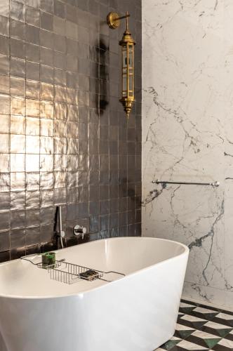 a white tub in a bathroom with a tiled wall at Riad Dar Al Dall - This Time Tomorrow in Marrakech in Marrakech