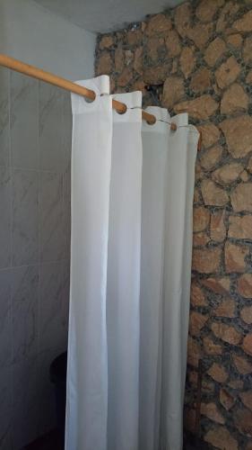 a pair of white curtains hanging from a stone wall at Paraíso Verde in Tambaca