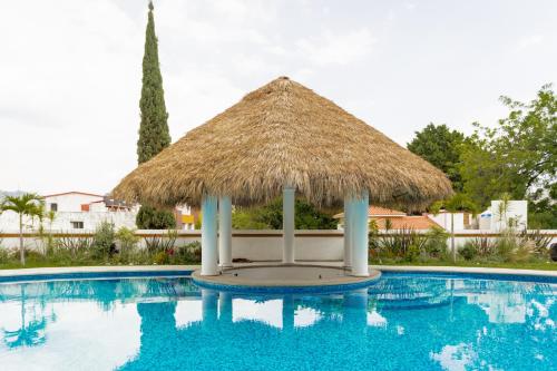 a large swimming pool with a thatch hut at Palacio Del Cobre in Tepoztlán