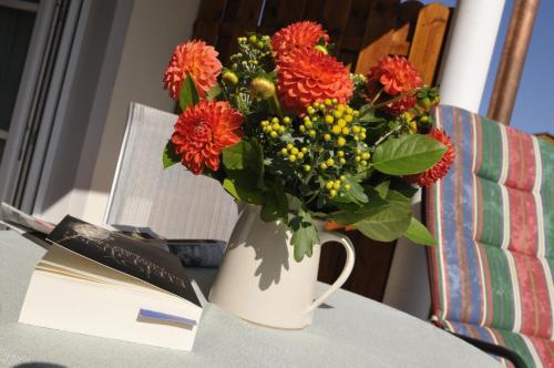 a vase of flowers on a table next to a book at Boutique Hotel Angerer in Murnau am Staffelsee