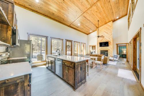 a kitchen with wooden ceilings and a living room at Broken Bow Cabin about 5 Mi to State Park with Hot Tub! in Broken Bow