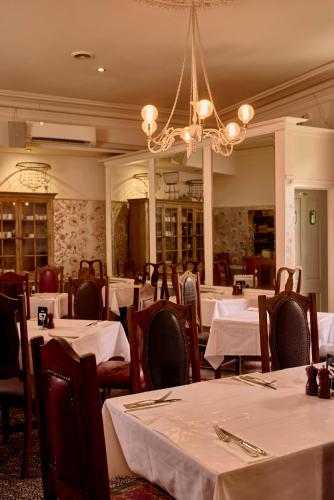 a restaurant with white tables and chairs and a chandelier at Yarra Valley Grand in Yarra Glen