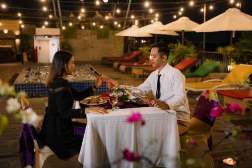 a man and a woman sitting at a table with food at Horison Ultima Seminyak Bali - CHSE Certified in Seminyak