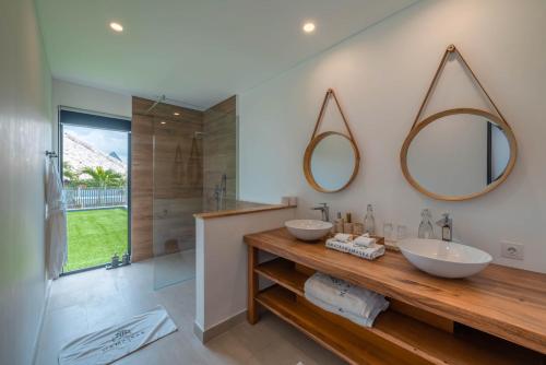 a bathroom with two sinks and two mirrors on the wall at Villa Namaskar - Iconic 5BR Cliff Top Villa - 180° Ocean View in Jimbaran