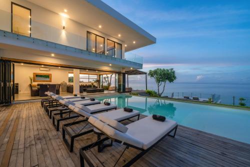 Villa Namaskar - Iconic 5BR Cliff Top Villa - 180° Ocean View في جيمباران: فيلا بمسبح وكراسي صالة