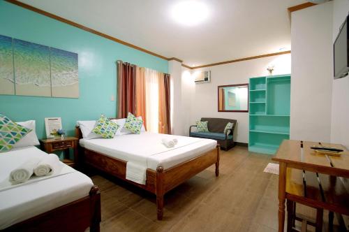 een kamer met 2 bedden, een tafel en een bureau bij ISLANDS VIEW INN in Coron