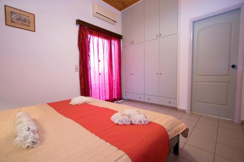 a bedroom with a bed with a red blanket and a window at Mythos- Platanias- Hotel -Apts in Plataniás