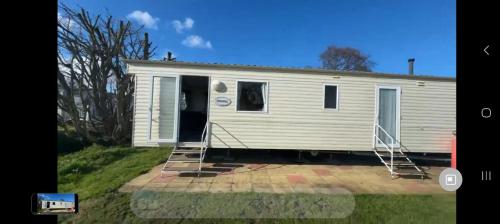 a mobile home with the door open in a yard at Cosy holiday home stay in Great Clacton