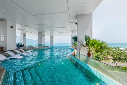 una piscina infinita en un hotel con sillas y el océano en Awaken Da Nang Hotel, en Da Nang