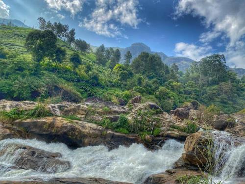una cascada en el lateral de una montaña con rocas en CJ Cottage Munnar - Near Attukal Waterfalls, Athukad Tea Estate (CJ Hotels & Resorts), en Devikolam