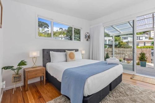 a bedroom with a bed and a large window at Escape to Kohi Cottage - Your Beachside Haven in Auckland