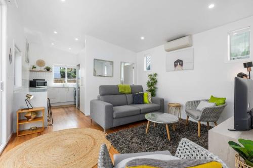 a living room with a couch and a table at Escape to Kohi Cottage - Your Beachside Haven in Auckland
