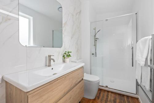 a bathroom with a sink and a toilet and a mirror at Escape to Kohi Cottage - Your Beachside Haven in Auckland