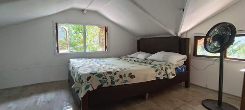 um quarto com uma cama no sótão e uma ventoinha em Jorge & Pony House 2 em El Nido