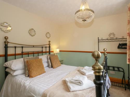 a bedroom with a bed with white sheets and a chandelier at Coronation Cottage in Wisbech
