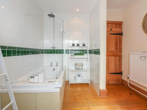 a white bathroom with a tub and a toilet at Coronation Cottage in Wisbech