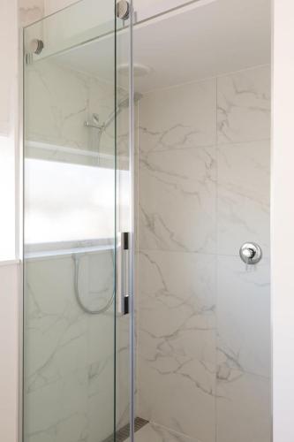 a shower with a glass door in a bathroom at Stay Coastal - Apartments in Auckland