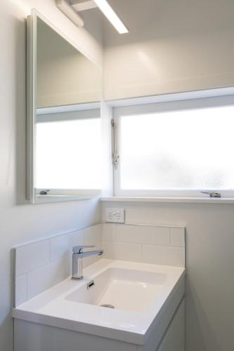 a bathroom with a sink and a mirror at Stay Coastal - Apartments in Auckland