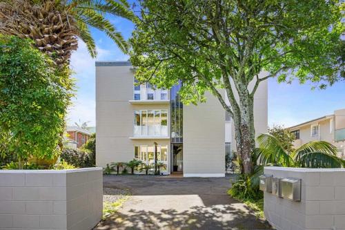 a white building with trees in front of it at Stay Coastal - Apartments in Auckland