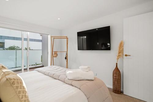 a bedroom with a bed with a flat screen tv on the wall at Luxury Apart, Seaviews & Balcony, Full Kitchen & Heat Pump in Auckland