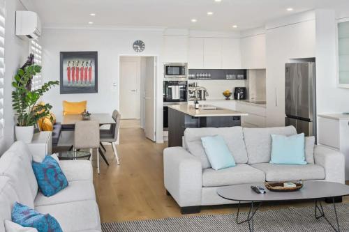 a living room with a white couch and a kitchen at Ocean View Spacious 5BR Retreat for Families in Auckland