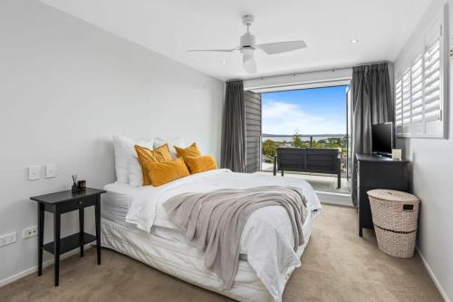 a white bedroom with a bed and a window at Ocean View Spacious 5BR Retreat for Families in Auckland
