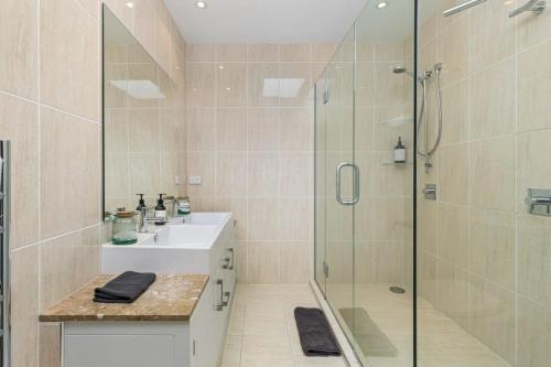 a bathroom with a shower and a sink and a glass shower stall at Ocean View Spacious 5BR Retreat for Families in Auckland