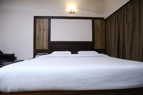 a large white bed in a bedroom with a window at WESTLAND HOTEL- ERODE in Erode