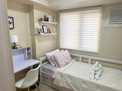 a small bedroom with a bed and a desk and a window at Stay comfy & feel Homealike #32 in Iloilo City
