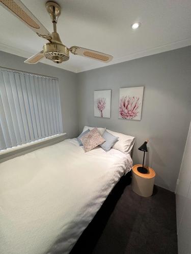 a bedroom with a white bed with a ceiling fan at Rockingham Palace in Rockingham