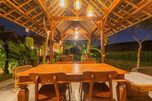 einen Holztisch und Stühle unter einem Holzdach in der Unterkunft Abian Ubud View in Ubud