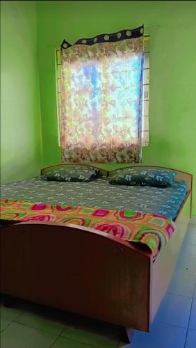 ein Bett mit zwei Kissen in einem Zimmer mit einem Fenster in der Unterkunft On Hill Rooms in Yercaud