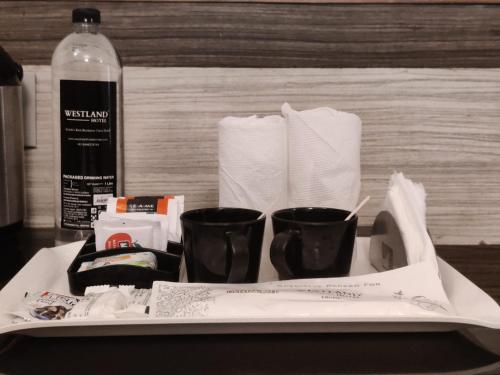 a tray with two cups and a bottle of alcohol at WESTLAND HOTEL- ERODE in Erode