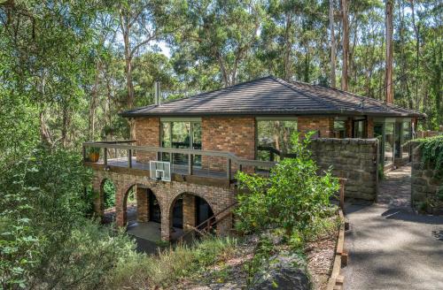 a brick house with a bridge in the woods at Elliott Lodge - Getaway for the whole family/pets in Upwey