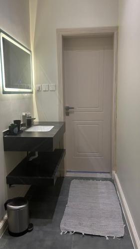 baño con lavabo, puerta y alfombra en نزل الزلفي لشقق المخدومة, en Az Zulfi