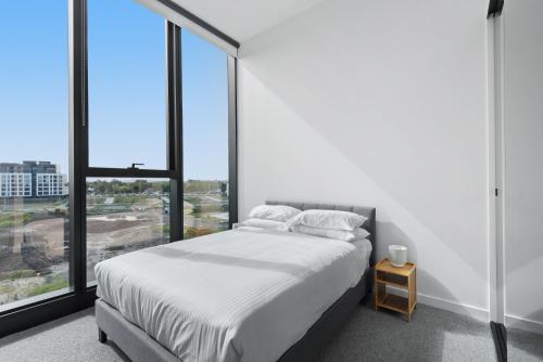 a bedroom with a bed and a large window at Generous 2-Bed Apartment with Great Amenities in Melbourne