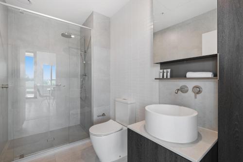 y baño con aseo blanco y ducha. en Generous 2-Bed Apartment with Great Amenities, en Melbourne