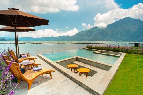 a swimming pool with tables and chairs and an umbrella at Agua Hotel in Kubupenlokan